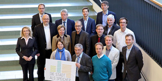 Gruppenfoto, zwei Personen halten Schild mit Logo "Stadt als Speicher" in der Hand