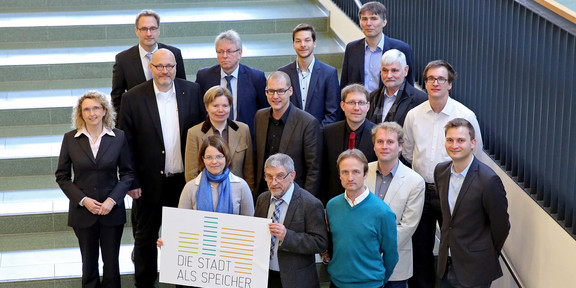 Gruppenfoto, zwei Personen halten Schild mit Logo "Stadt als Speicher" in der Hand