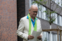 Ein Mann in hellem Anzug hält vor einem Gebäude der TU Dortmund eine Rede