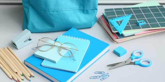 Brille, die auf blauen Schulmaterialien liegt