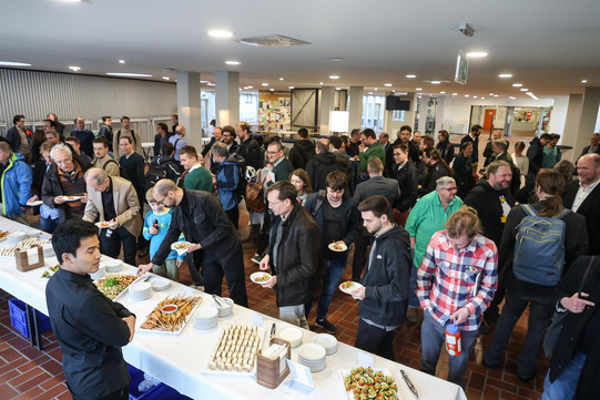 Eröffnung DoBaS Mehrere Personen bedienen sich im Foyer eines Universitätsgebäudes an einem Buffet.