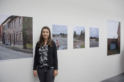 Preisträgerin vor fünf Fotografien. 