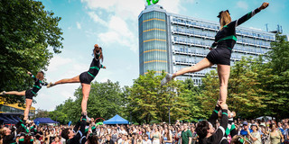 Cheerleader in bunten Outfits bei einem Auftritt auf dem Campus Nord der TU Dortmund, umgeben von Zuschauern