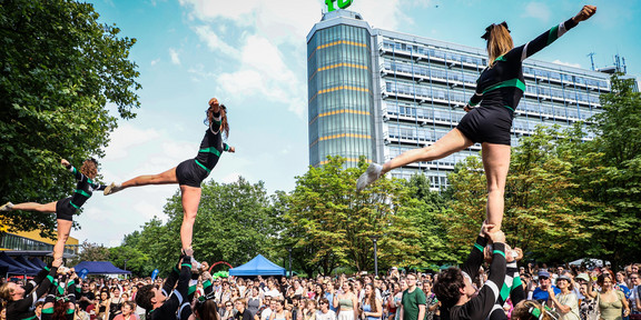 Cheerleader in bunten Outfits bei einem Auftritt auf dem Campus Nord der TU Dortmund, umgeben von Zuschauern