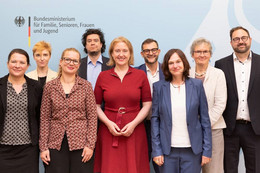 Juli Eine Gruppe von Menschen vor einem Banner des Bundesministeriums für Familie, Senioren, Frauen und Jugend