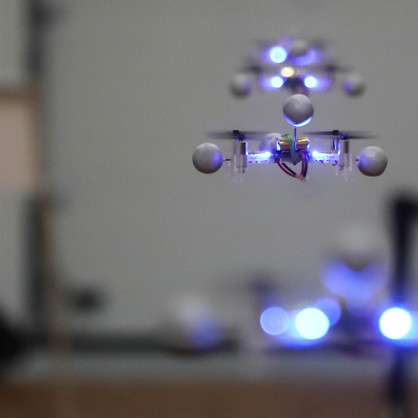 Several drones fly in a row one after the other with a bluish glow
