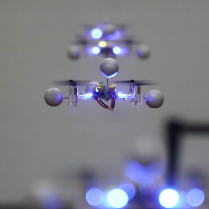 Mehrere Drohnen fliegen hintereinander in einer Reihe und leuchten dabei bläulich