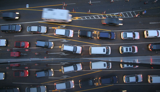 Autos im Stau Es sind mehrere Autos in einer Schlange auf einer Autobahn von oben abgebildet.