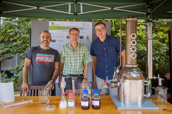 Drei Männer stehen nebeneinander hinter einem Stand.