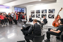 Musiker treten bei der Ausstellungseröffnung vor den Besuchern auf (Akkordeon, Geige, Keyboard).