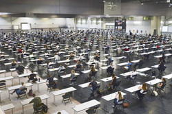 A large hall full of students sitting at tables.