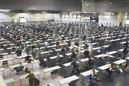 Studierende sitzen mit Abstand zueinander an Tischen, um eine Klausur zu schreiben.