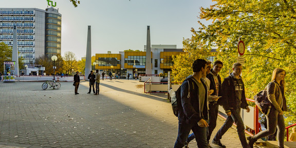 Studierende laufen über den herbstlichen Campus
