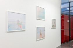 In einer Ausstellung hängen Bilder an einer weißen Wand.
