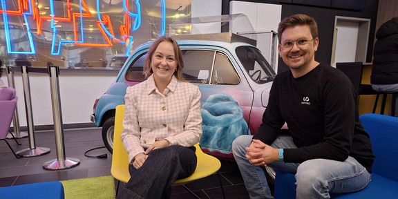 Foto: Michelle Twardzik und Dr. Thomas Seidensticker sitzen in auf einer blauen Couch und einem gelben Stuhl und lächeln in die Kamera.