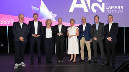 Gruppenfoto mit acht Personen auf einer Bühne, im Hintergrund steht AI24