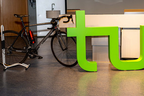 Ein E-Bike steht neben dem Logo der TU Dortmund in einem Hörsaal.
