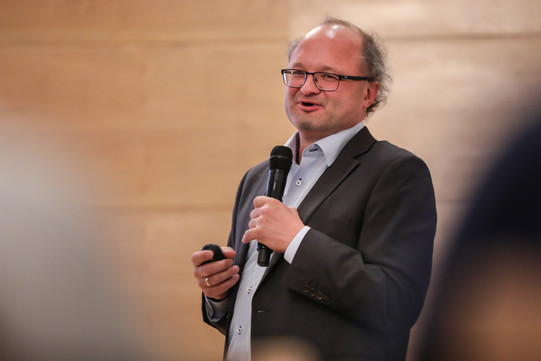 Gambrinus-Forum Ein Mann im Anzug hält ein Mikrofon in der Hand und spricht.