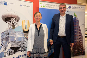 Prof. Tessa Flatten und Wulf-Christian Ehrich stehen vor einem Aufsteller der IHK und der TU Dortmund.