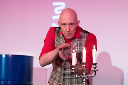 A man stands behind a candlestick with three candles.