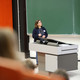 Eine Frau hält in einem Hörsaal eine Präsentation.