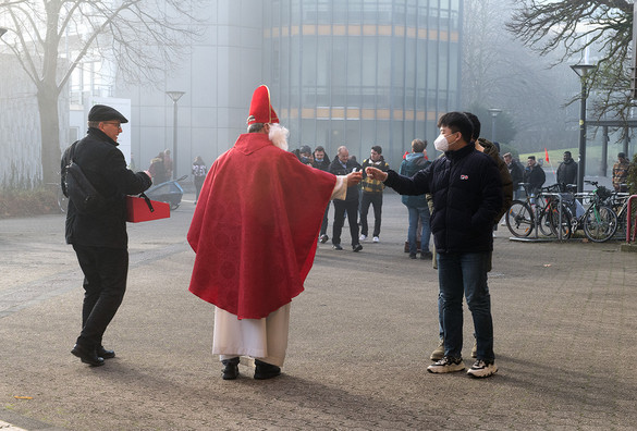 Der Nikolaus gibt einem Studenten einen Schoko-Nikolaus.