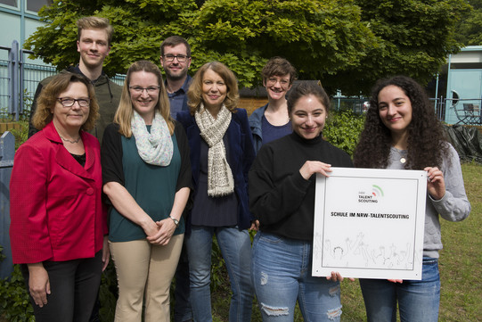 Foto von Personen und zwei Schüler*innen halten eine Auszeichnung