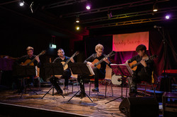 Vier Gitarrenspieler auf einer Bühne