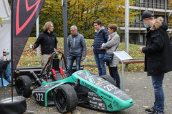 Several people are standing around a race car outside.