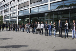 Die neuen Auszubildenden der TU Dortmund stehen aufgereiht vor einem Gebäude.