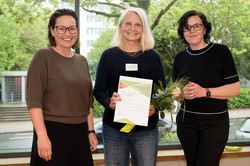 In the photo, three people are smiling at the camera after the certificates were presented.