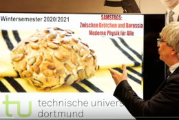 Ein Mann zeigt eine Präsentation. Auf den Folien sieht man ein Brötchen.