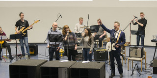 Weihnachtsvorlesung Eine Band mit Sängern, Gitarre, Schlagzeug, Klavier und Flöte.