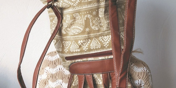 Titelbild der Ausstellung "Textil; Design; Alltag": Person mit gehäkeltem Oberteil, der ein Rucksack über den Kopf gestülpt ist.