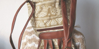 Titelbild der Ausstellung "Textil; Design; Alltag": Person mit gehäkeltem Oberteil, der ein Rucksack über den Kopf gestülpt ist.