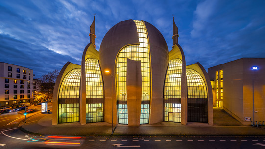 Eine hellerleuchtete Moschee bei Nacht. 