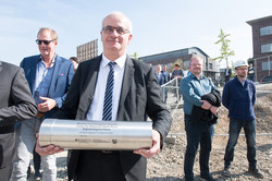 A man followed by other people carries a time capsule.