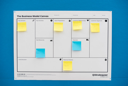 A large printed spreadsheet with post it notes on a blue wall
