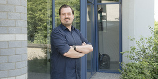 Alexander Michalik steht vor einem Gebäude auf dem TU-Campus.