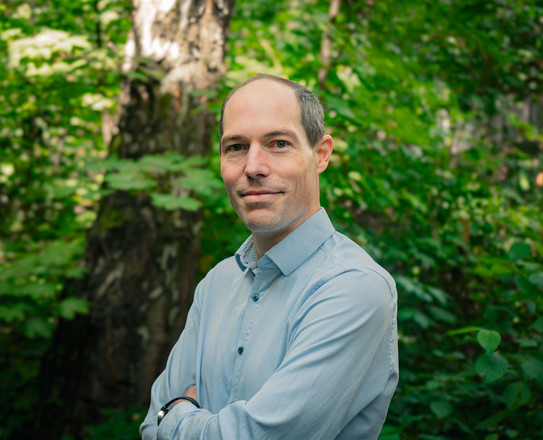 Portrait photo of Prof. Armin Lühr: Prof. Lühr is wearing a light blue shirt and standing in a green forest.