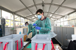 Testpersonal Mitarbeiter des Testpersonals in Schutzkleidung und mit Testmaterialien in der Hand