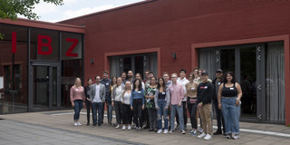 Several students from different countries are standing in front of a building.