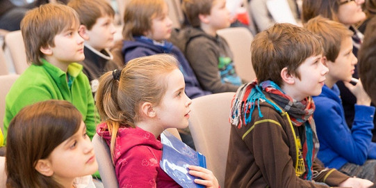Grundschüler sitzen in einem Hörsaal