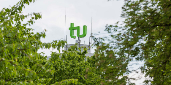 TU Logo MAthetower TU-Logo auf dem Mathetower, im Vordergrund Blattwerk