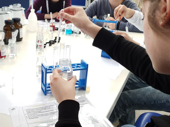 Eine Person füllt Flüssigkeit mit einer Pipette in ein Reagenzglas.