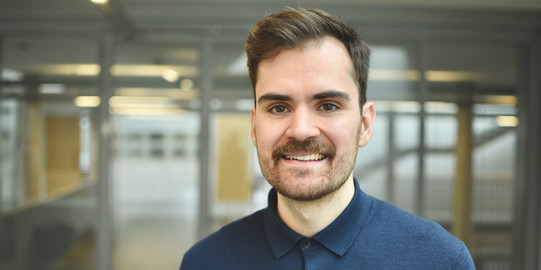Portrait of Associate Professor Tim Heubeck: Associate Professor Heubeck has brown hair and is wearing a blue top.