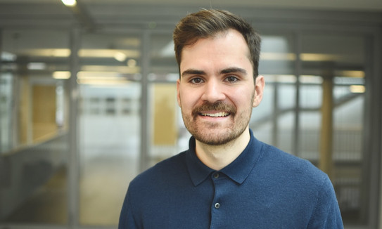 Portrait of Associate Professor Tim Heubeck: Associate Professor Heubeck has brown hair and is wearing a blue top.