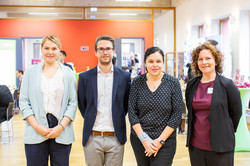 Gruppenfoto Vier Menschen stehen in einer Reihe und lächeln in die Kamera