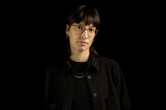 Porträtfoto von Prof. Magdalena Zabek: Porf. Zabek trägt eine Brille und dunkle Kleidung. Sie steht vor einem schwarzen Hintergrund.