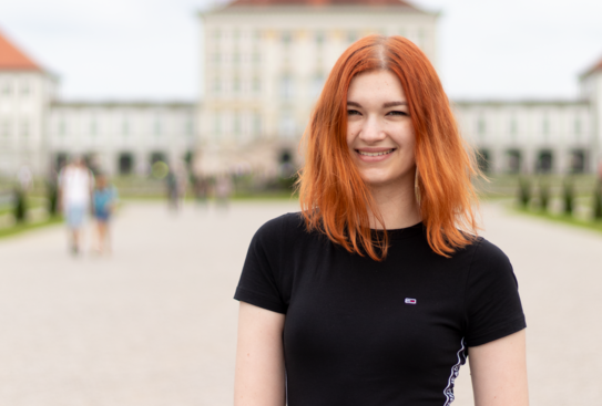 Lena Zaubzer Eine Frau mit roten Haaren und schwarzen T-Shirt lächelt in die Kamera.